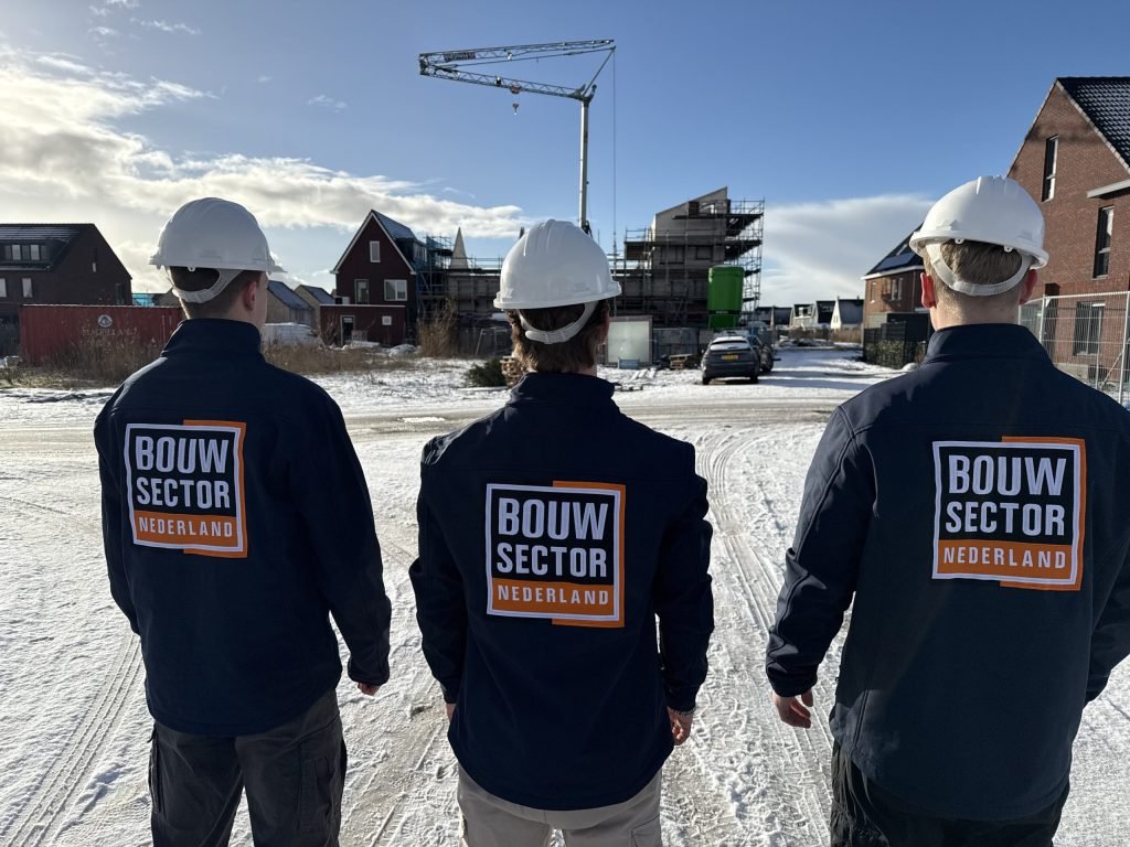 Drie vakmensen van Bouwsector Nederland met witte helm bij woningen in aanbouw